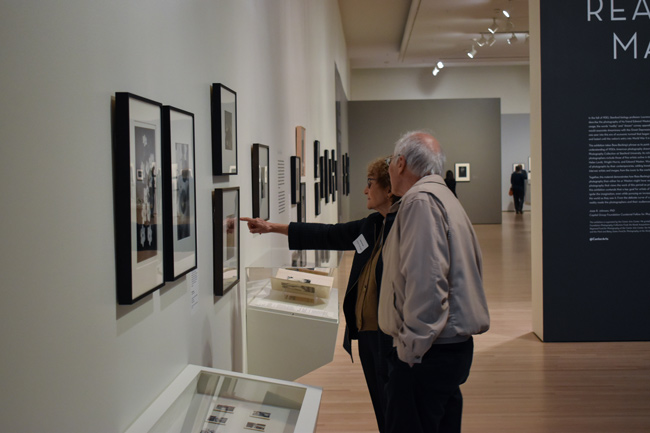 An image of two people looking at a painting inside of a gallery