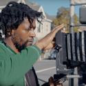 An image of a black man preparing to take a picture on the street