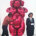 an image of a gallery depicting a sculpture and a security guard and cleaning person