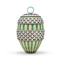 An intricately woven oval basket with a lid and top ring handle, featuring alternating bands of cream, bright green, and turquoise elements with protruding dark points against a plain white background.