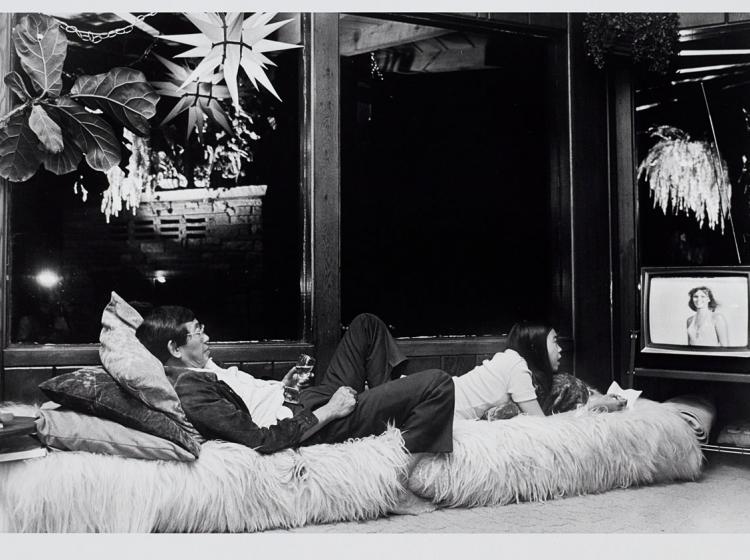 An image of two people laying down and watching TV