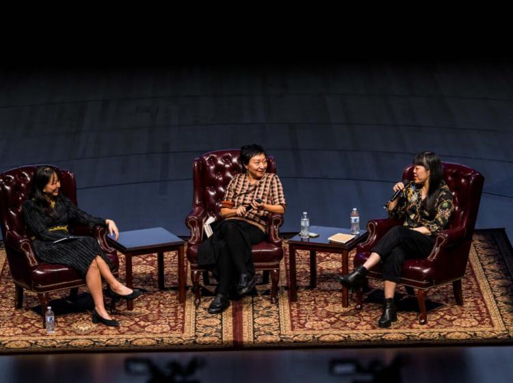 Three women on the stage during a symposium