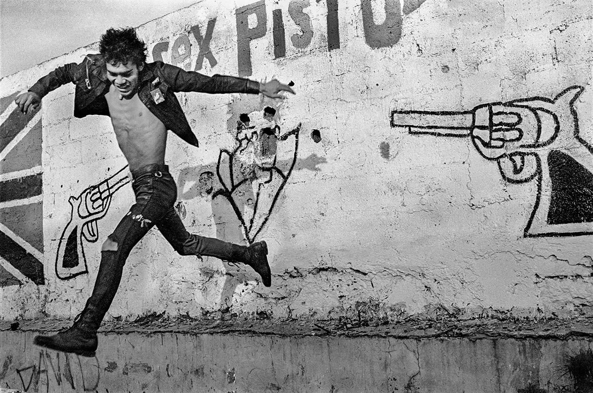 An image of a man jumping behind a wall with a pistol drawn on it