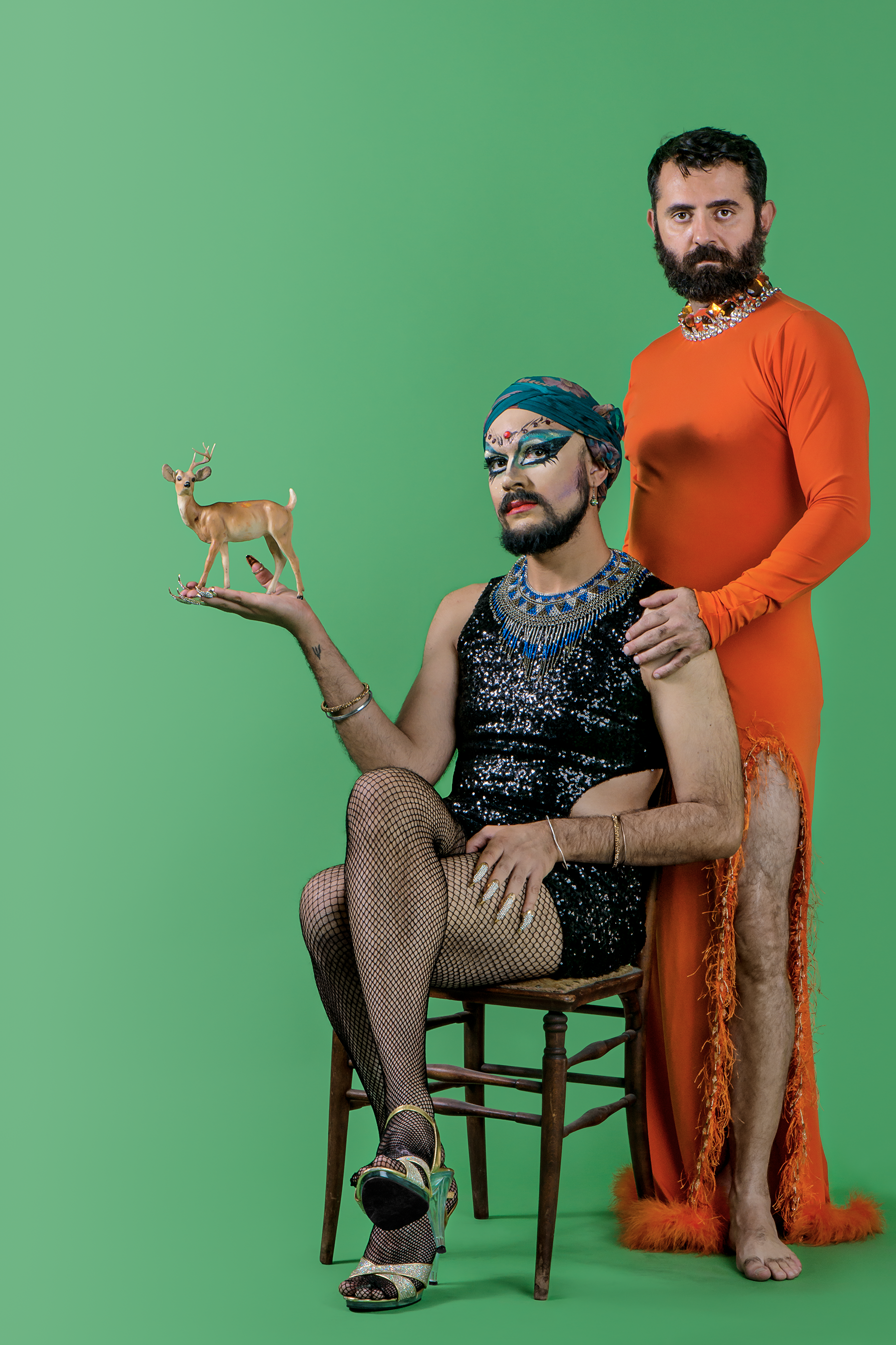 two men in women's clothing standing before a green background