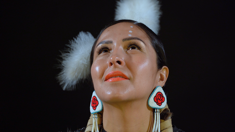 A image of a native american woman looking up with a black background
