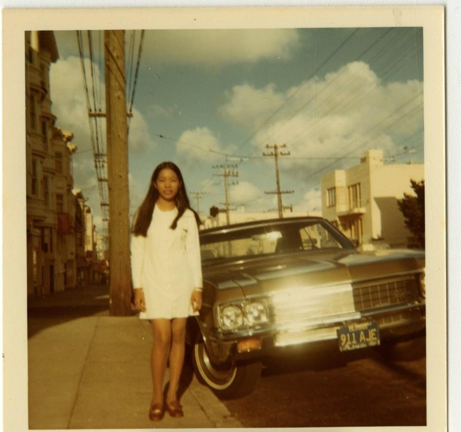 A woman next to a car on the sidewalk in SF